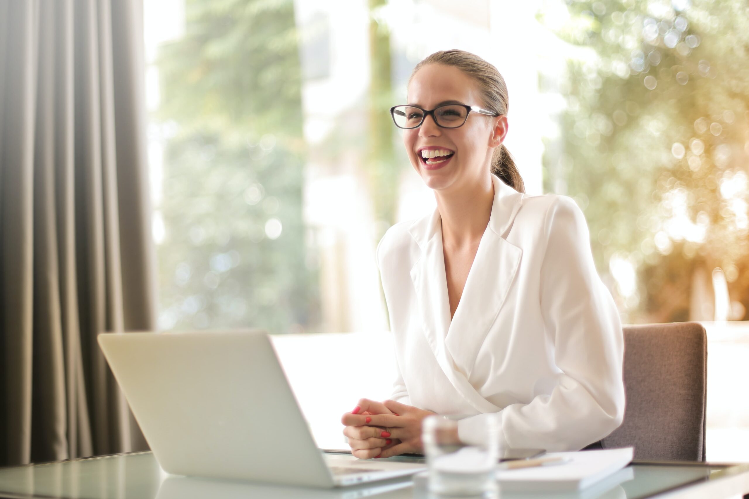 Image of business woman laughing sitting at laptop